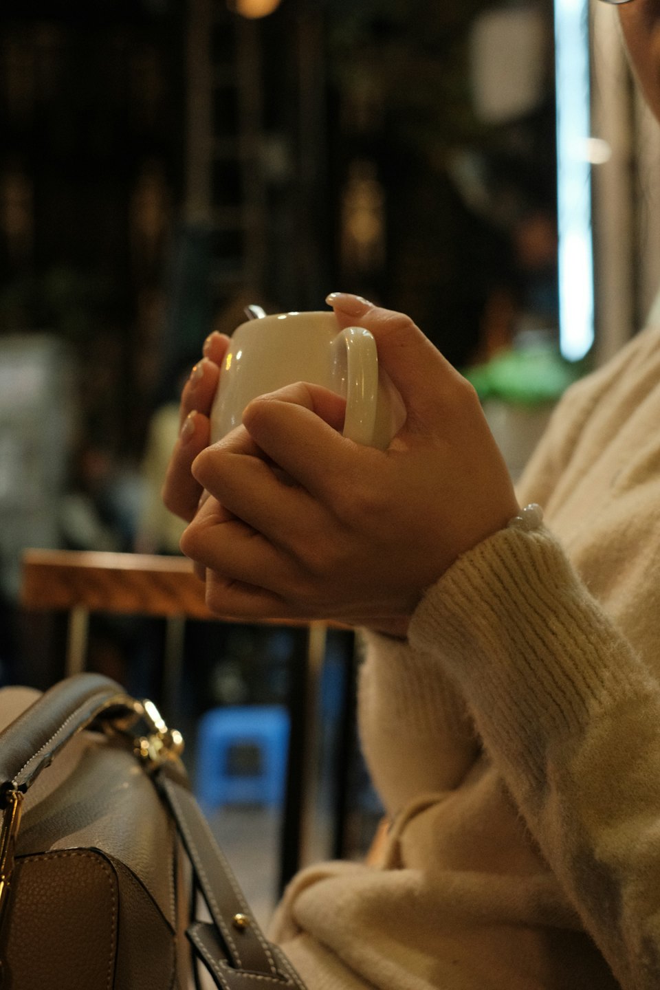 Hands in a knitted sweater hold a warm ceramic mug.